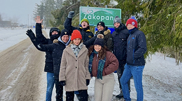 Brenna Brisson posing with her Global MBA cohort in front of a frosty Zakopane road sign