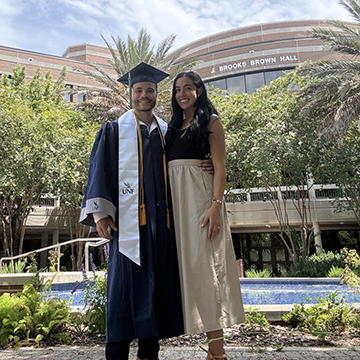 Michael Carrero in his cap and gown standing next to his wife Ariana Munoz