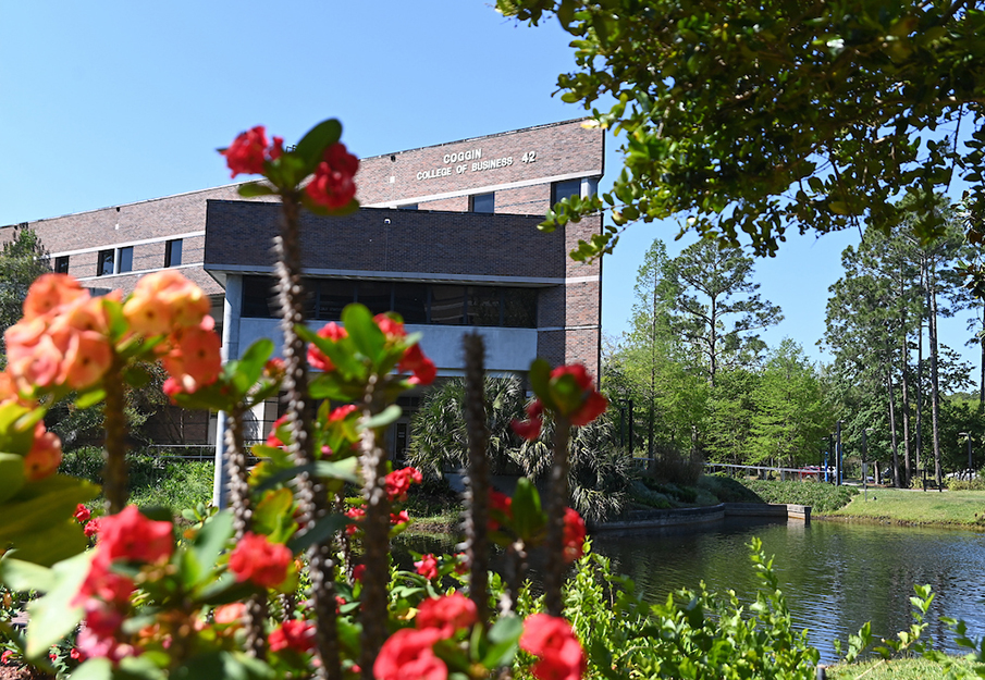Outside Coggin College of Business building with flowers in foreground