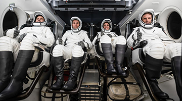 Delaney and crew in space suits inside spaceship