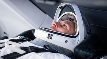 Close up of Delaney wearing space helmet sitting back