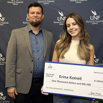 Erina Kotreli standing beside Dr. Szymon Ciesielski holding her reward for the 2026 Library Research Prize