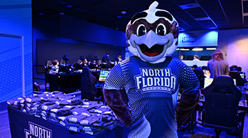 Ozzie standing in front of table of shirts in new Esports arena