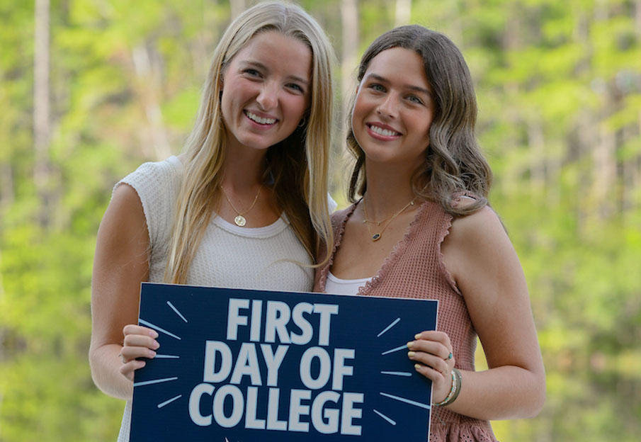 Two freshmen holding a First Day of College sign