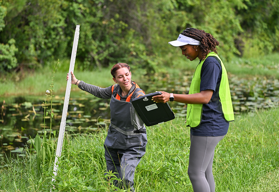 Two IERE students looking at clipboard while collecting data
