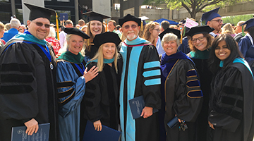 Lauren Church standing among peers and professors at graduation