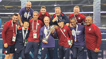 Lauren Church standing with US Men's Soccer Team holding trophy