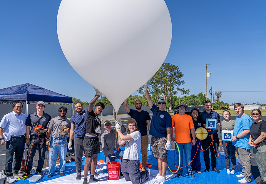 UNF engineering and physics students posing with Dr. Nirmul beside NASA balloon