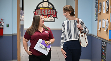 UNF and RCSA educators walking down hallway with a rocket ship logo behind them