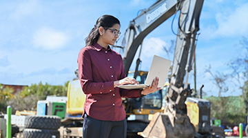 Alekhya Seelam typing on a laptop in front of a construction crane