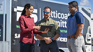 Alekhya Seelam showing laptop to a professor and Petticoat-Scmitt employee 