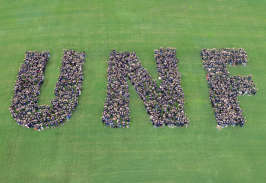 Faculty and staff standing together to create UNF letters from aerial view