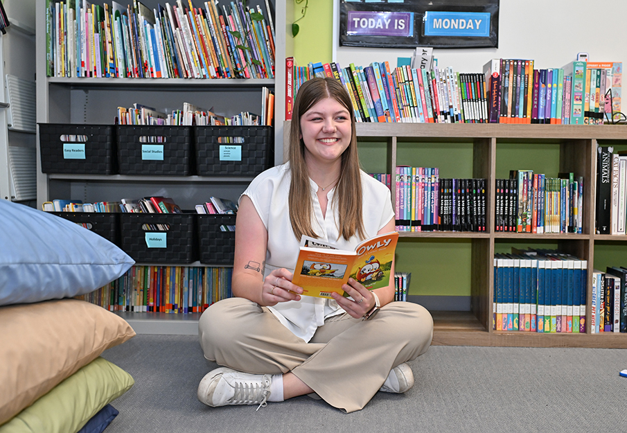 Mikayla Waters sitting in reading circle looking at a kids books