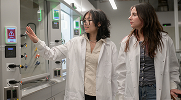 Two UNF students in white lab coats walking through chemistry lab
