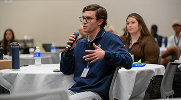 Student holding microphone while asking a question