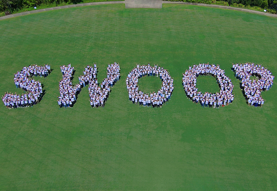 Faculty spelling SWOOP on green lawn