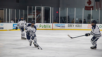 Three UNF Hockey players on the ice in full gear