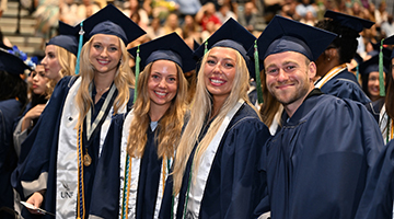 Four UNF graduates standing together