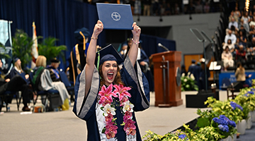 UNF graduate holding up her diploma excitedly