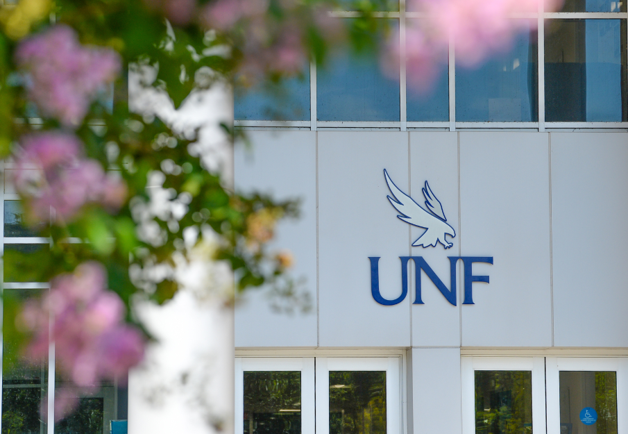 UNF building on campus that has the UNF logo on it with pink florals surrounding the building