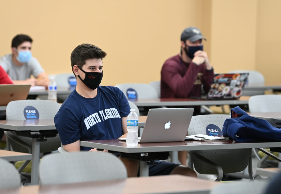 Student wearing a face mask in a classroom with a laptop