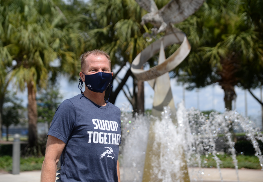 Male employee wearing UNF attire and a face mask by the Osprey Fountain