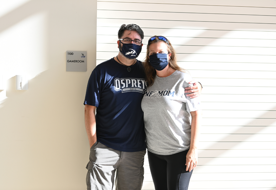 Two parents in UNF dad and UNF mom t-shirts with face masks