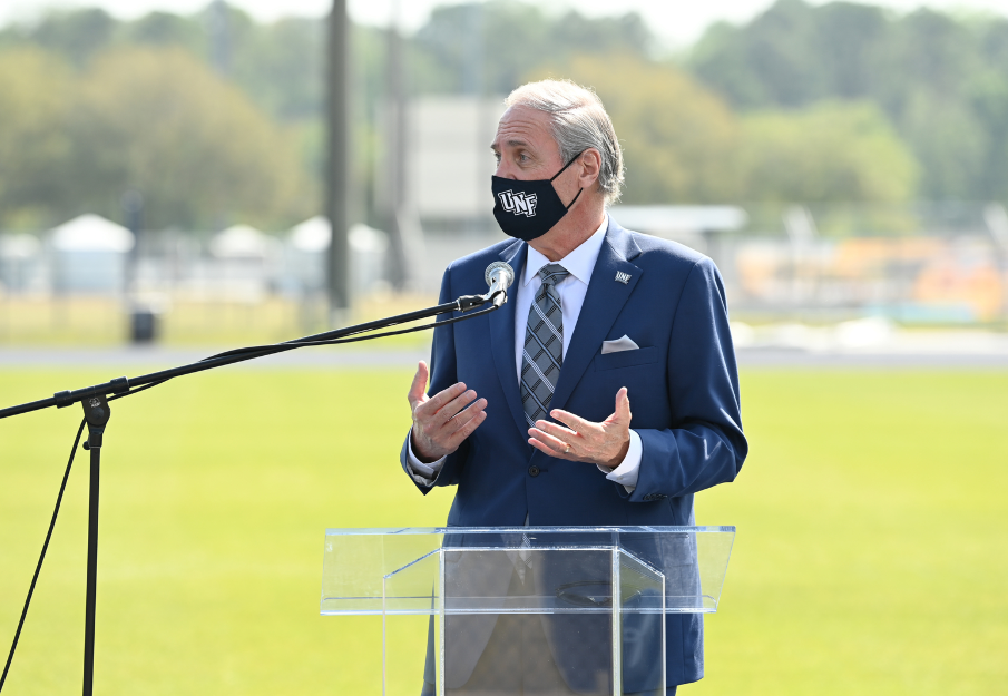 UNF President David Szymanski standing at an outside podium speaking to a crowd