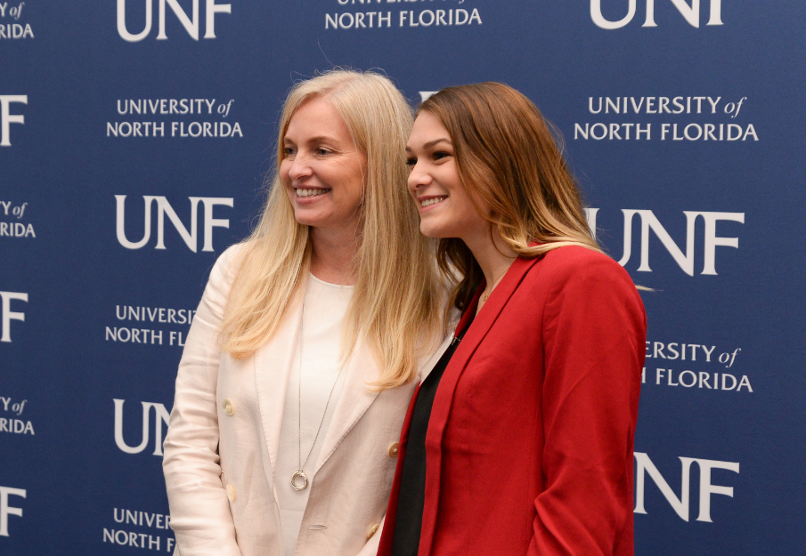 Two women standing in front of a UNF logo backdrop smiling