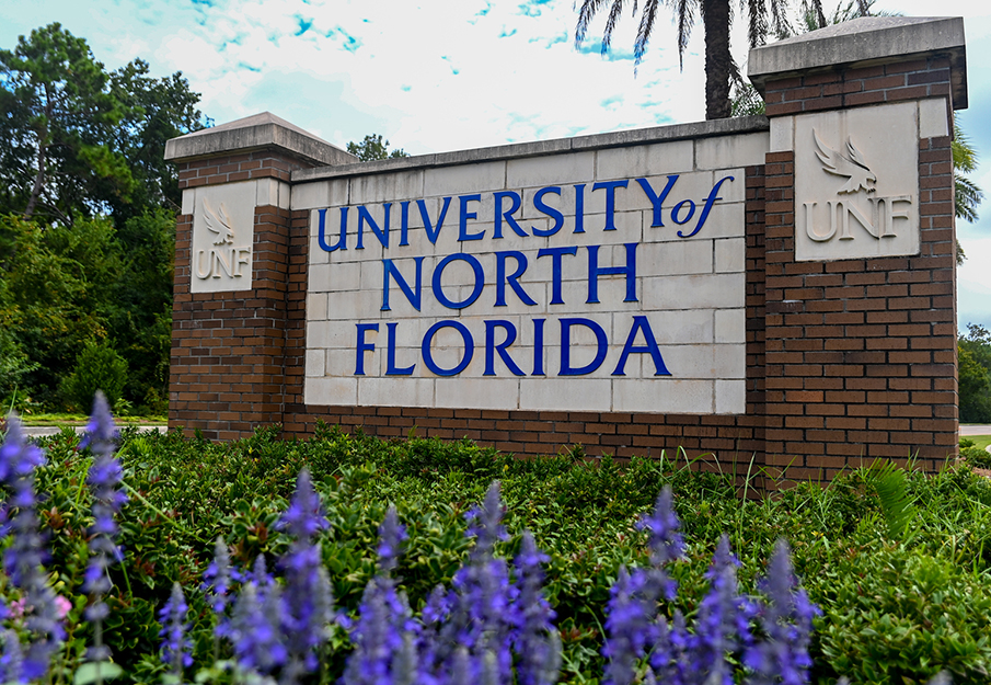 UNF entrance sign with purple flowers in the foreground