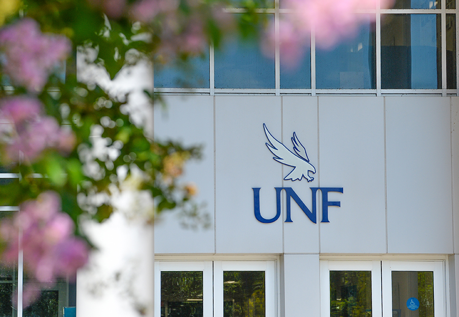 Building on campus with a UNF logo and pink flowers outside