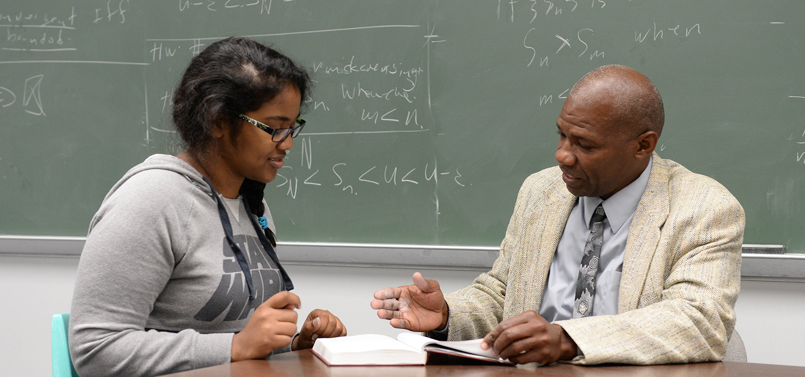 student and professor looking at a book