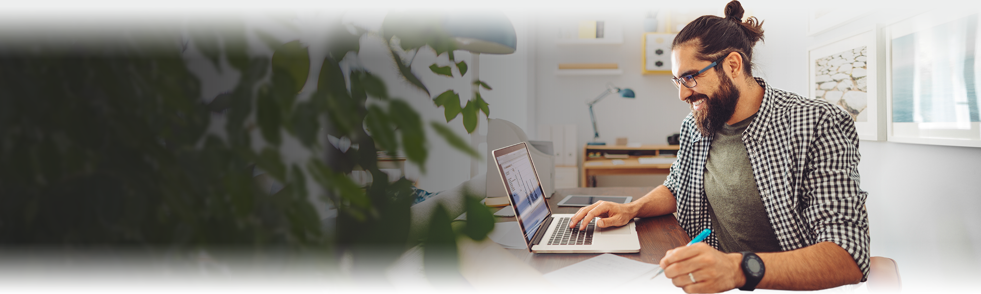 married man smiling and studying online at his home desk