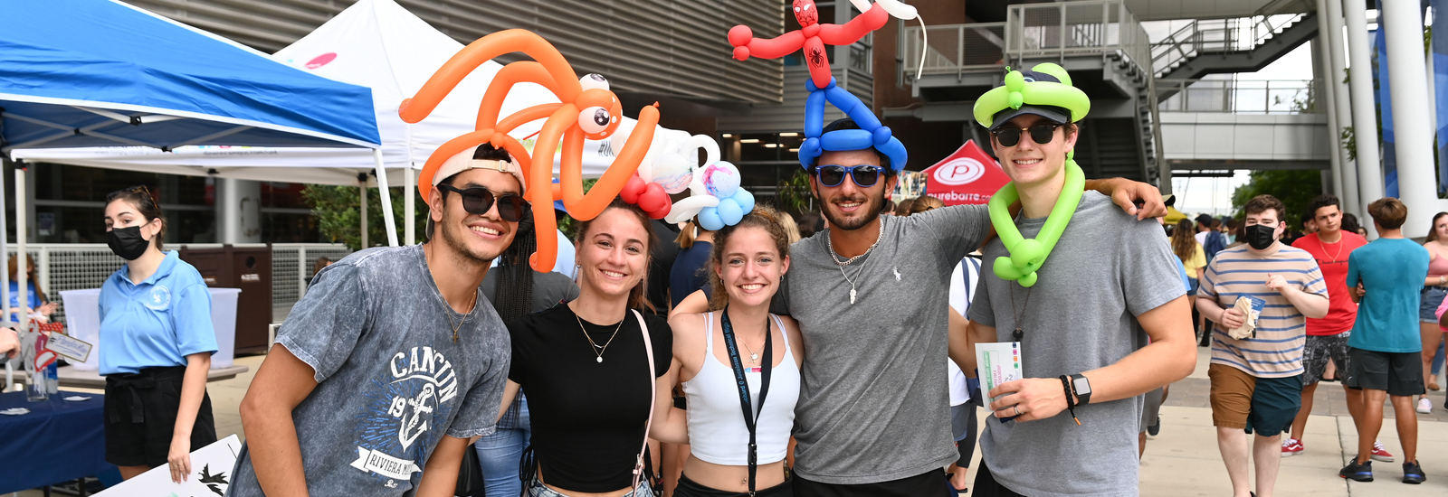Group of students in the UNF student union plaza with balloon hats on and smiling