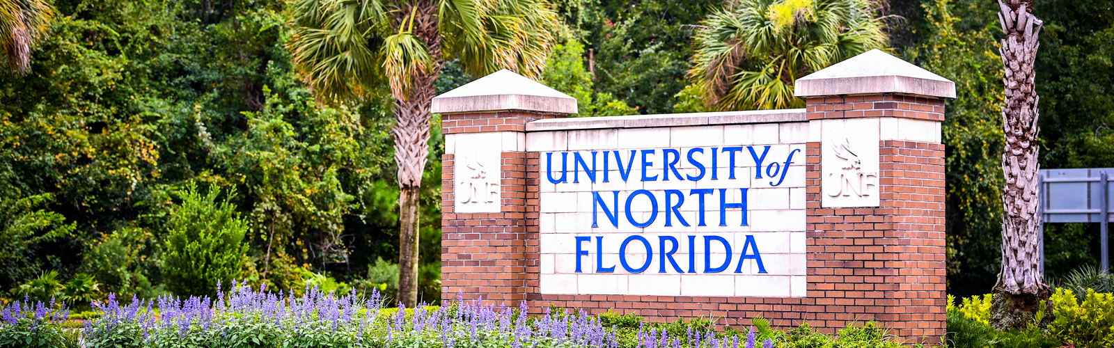 University of North Florida brick entrance sign surrounded by palm trees