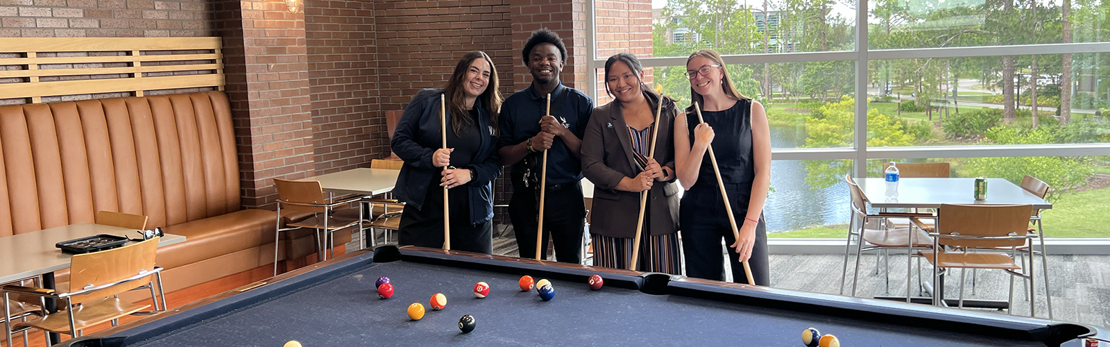 Staff members standing behind a pool table