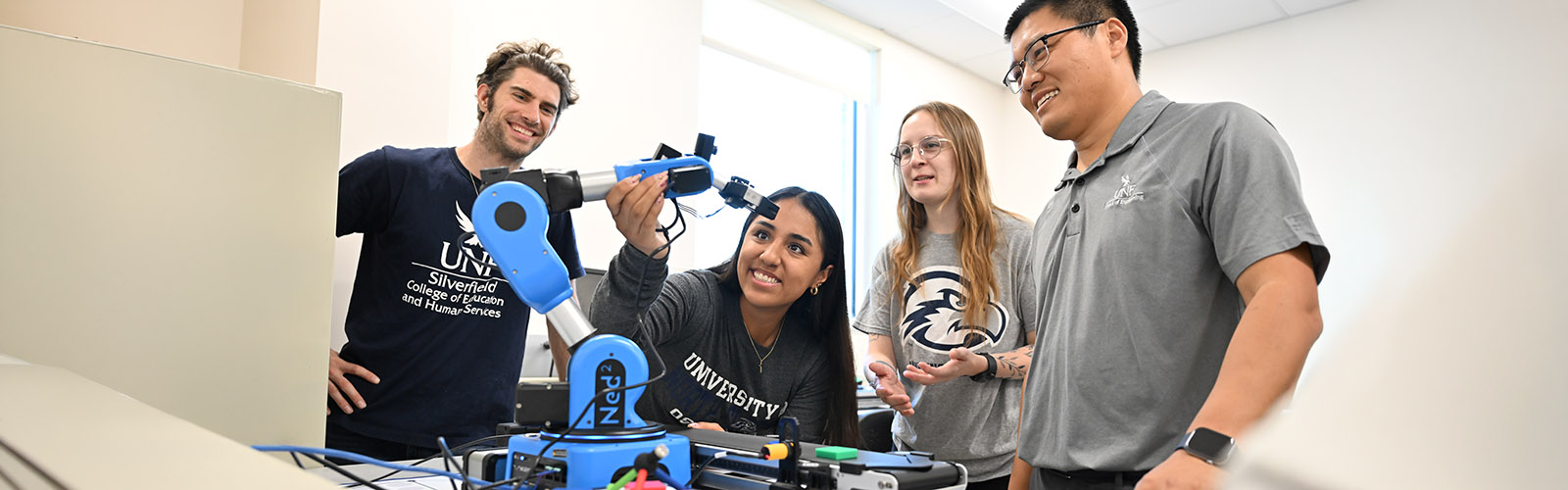 four students working on a robotic arm