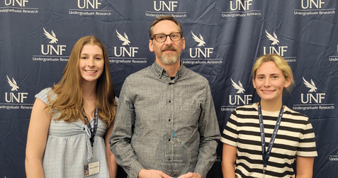 Dr.  John Hatle posing with his award and two students