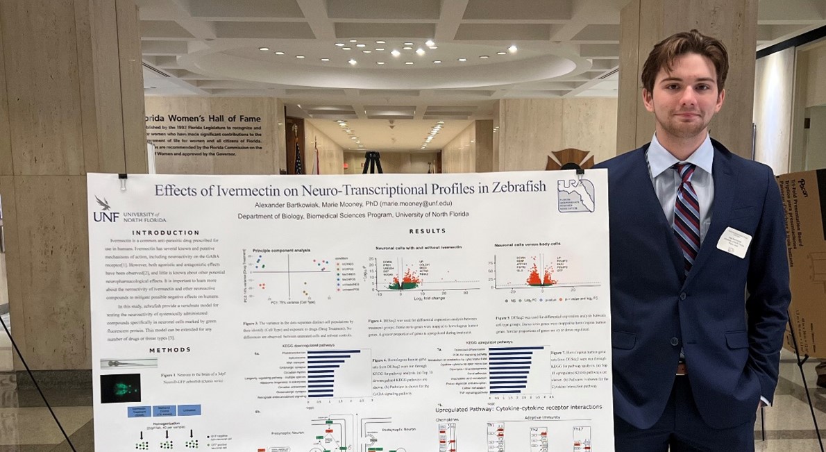 alex standing by his research board at a conference