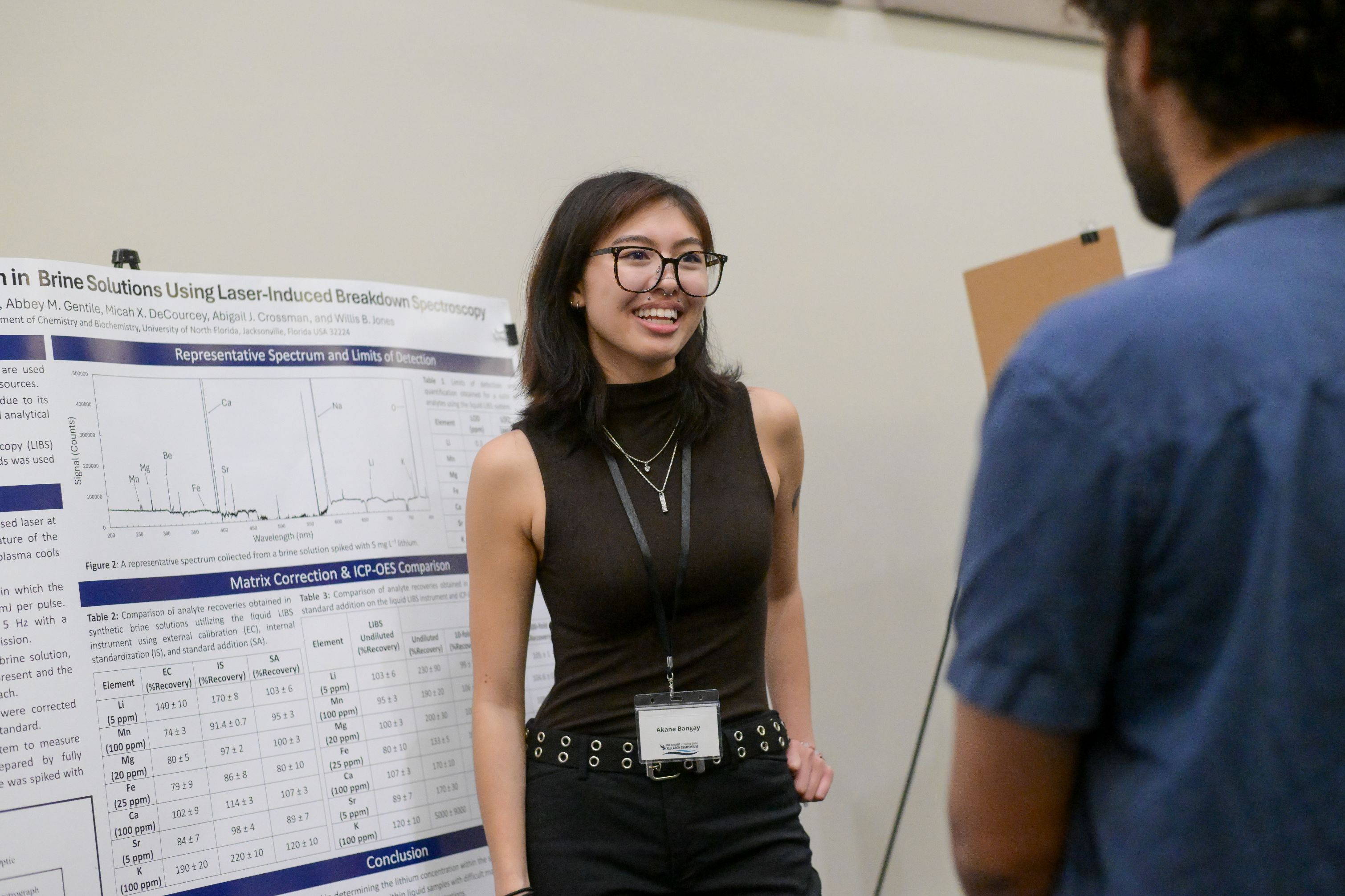 A woman is talking to a student near her research poster.