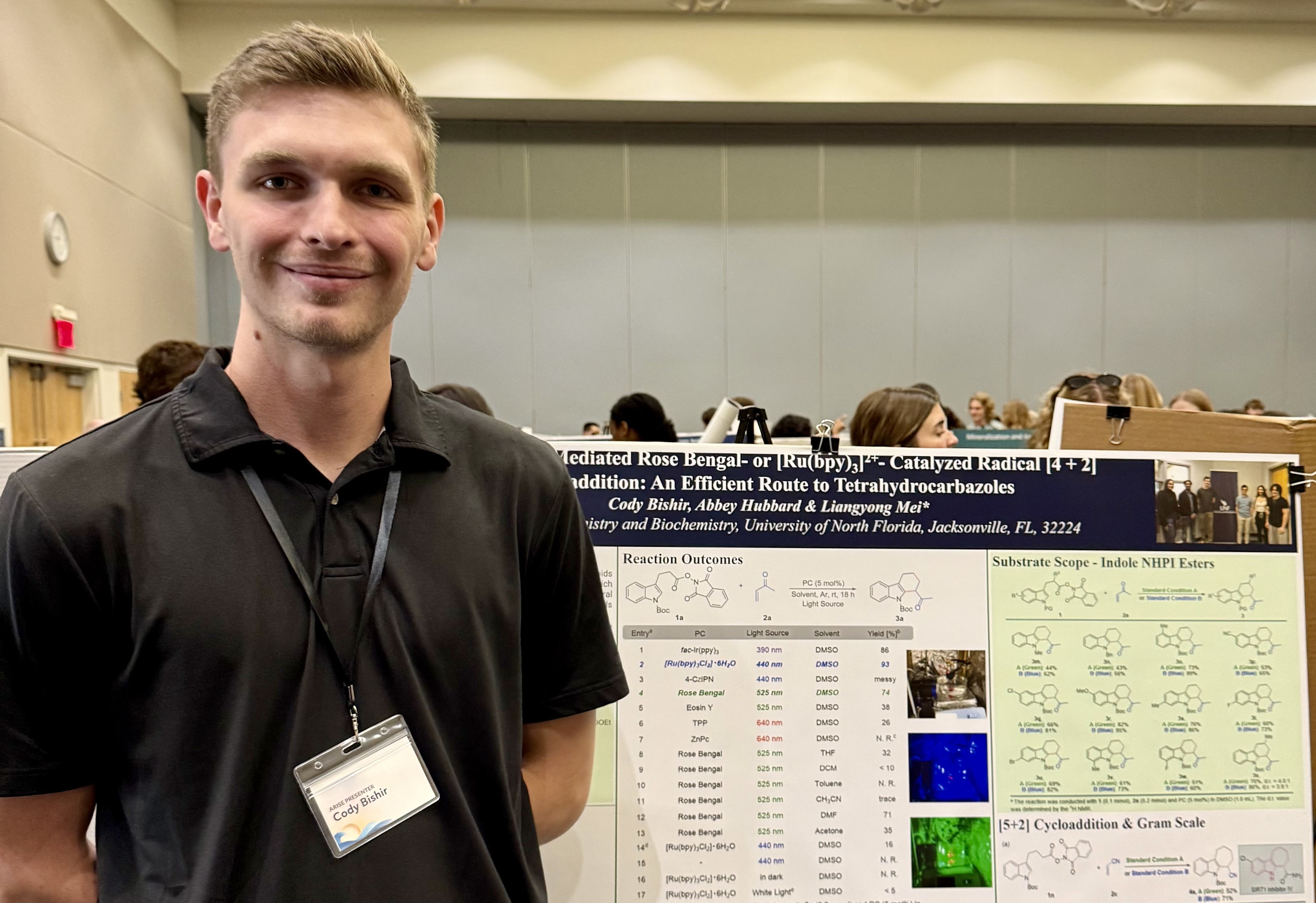 Cody standing in front of his research poster and smiling.
