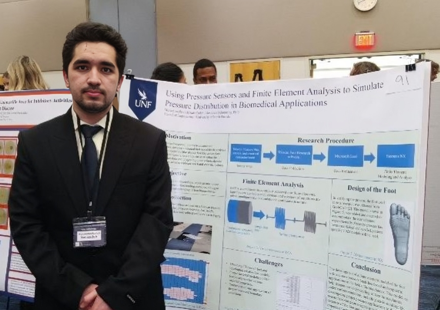 Nabi standing in front of a board his is research findings
