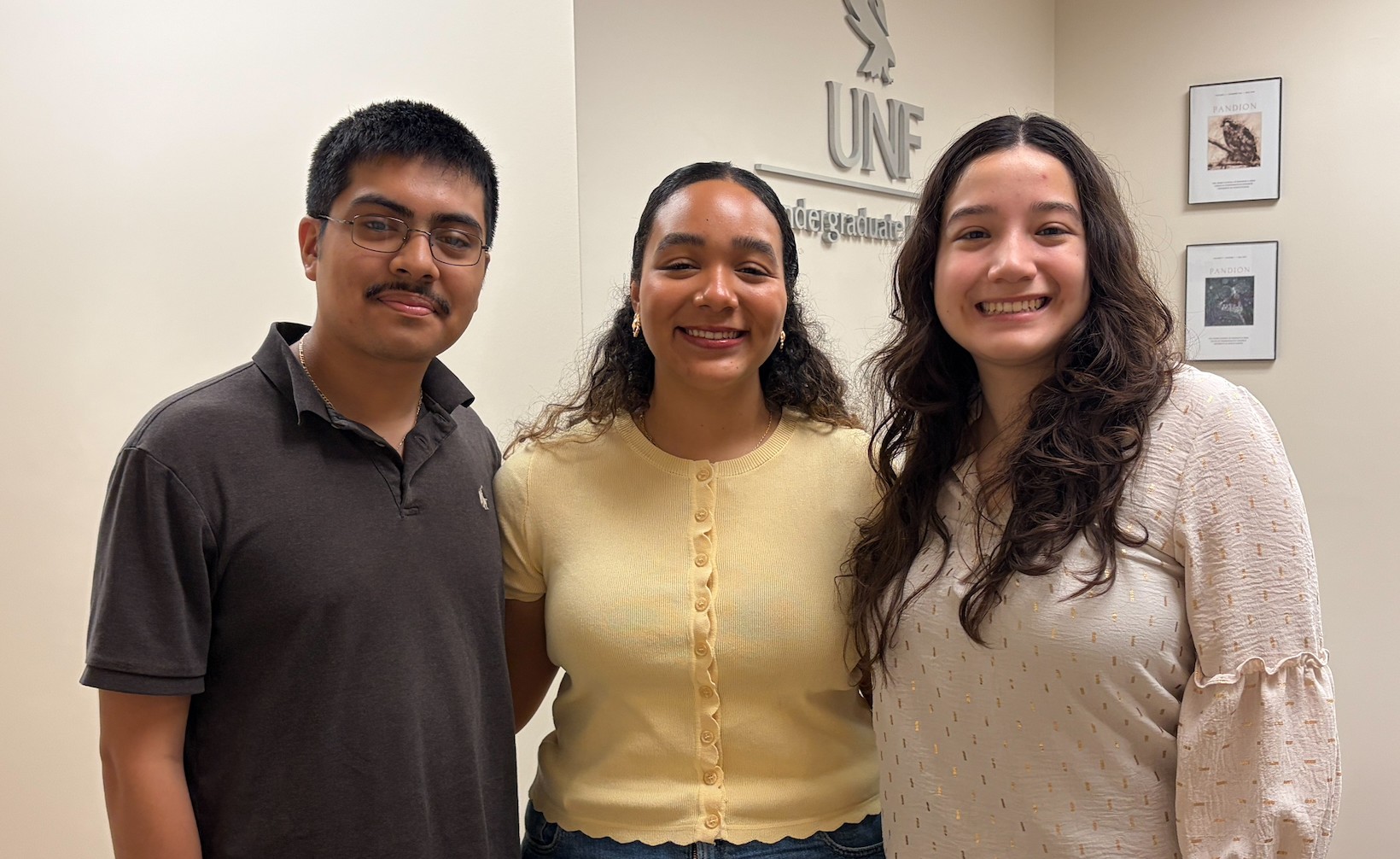 A man and two women are posing for a picture in an office.
