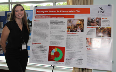 Susie standing in front of her research poster and smiling.