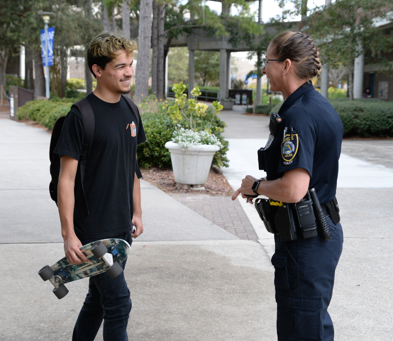 UNF student holding a skateboard and smiling while talking to a female UNF Police Officer