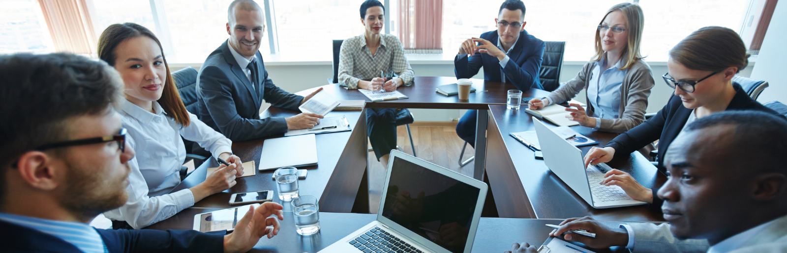 Group of employees having a meeting around a group of tables with computers
