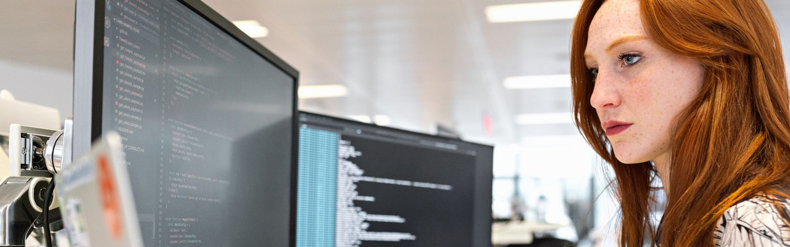 female computer programmer looking at two computer screens