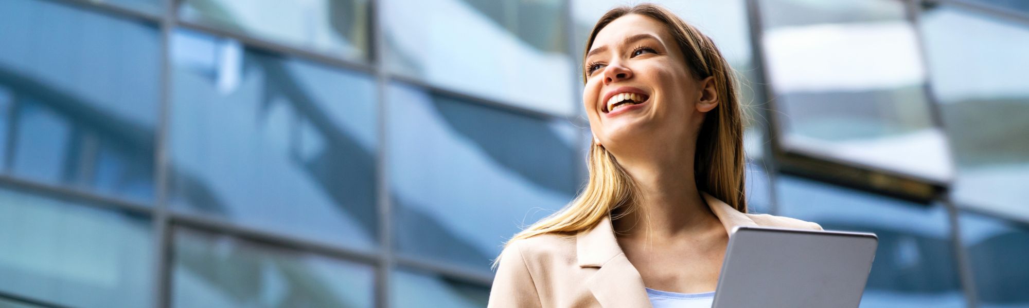Young business woman using tablet in front of business building