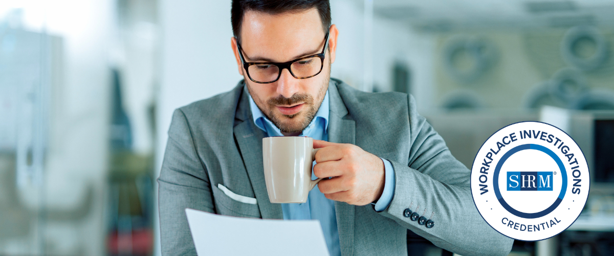 Man with a cup of coffee reading a document