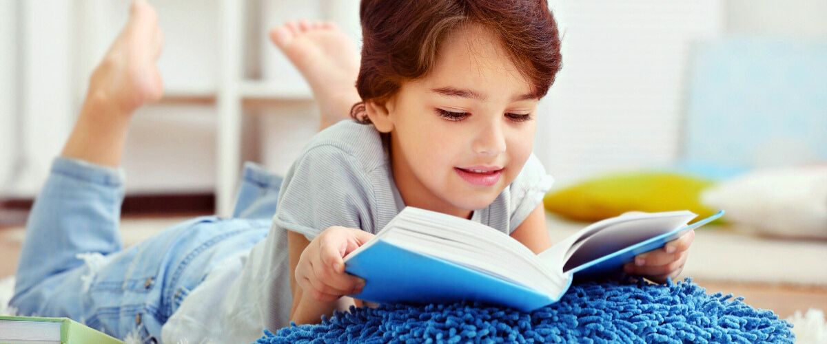 Boy enjoying reading a book with blue cover